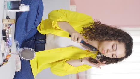 Vertical-video-of-Young-woman-combing-her-hair.-Hair-care.